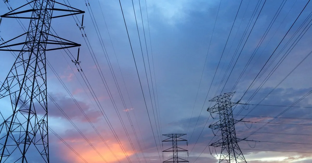 Lignes a haute tension au coucher du soleil, marche de l'electricite 2027 pour les entreprises